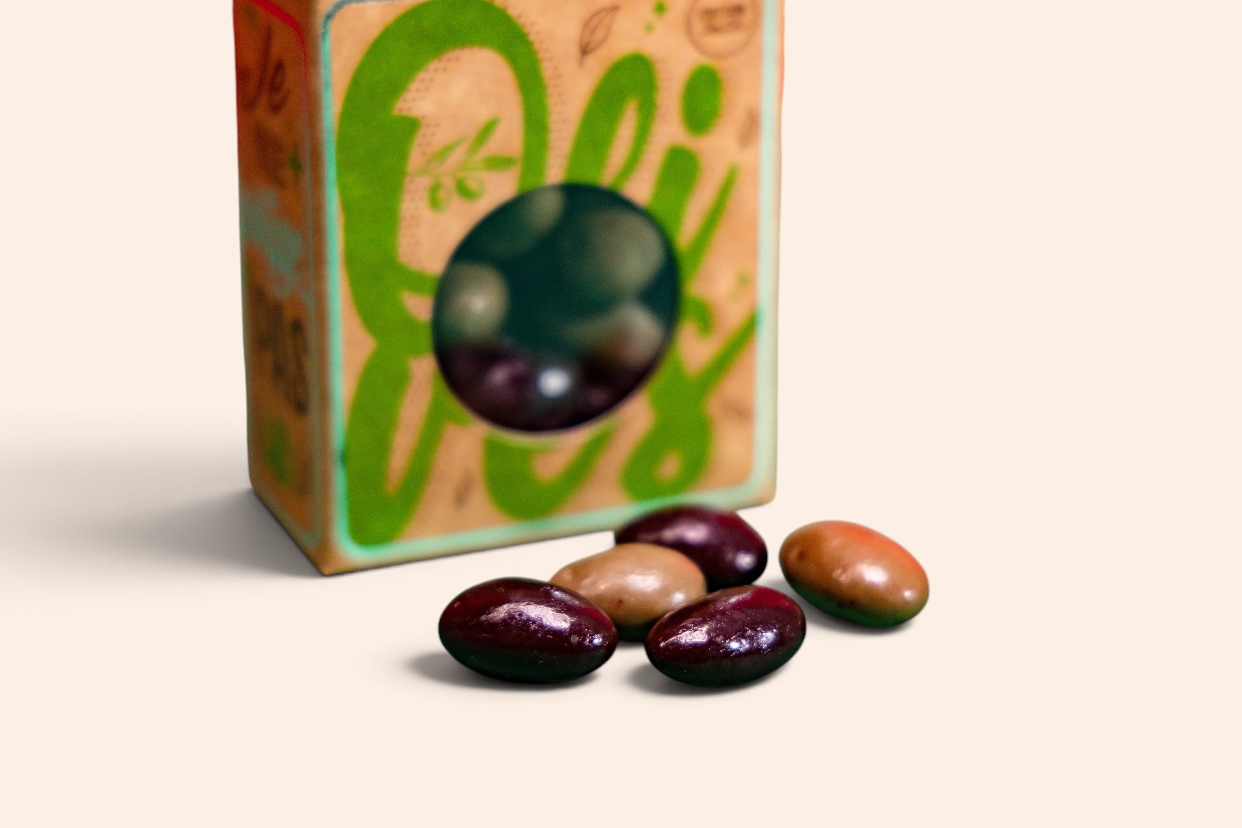Amandes torréfiées enrobées de chocolat noir Maison Fruidoraix, forme d'olives vertes et noires sur fond vert