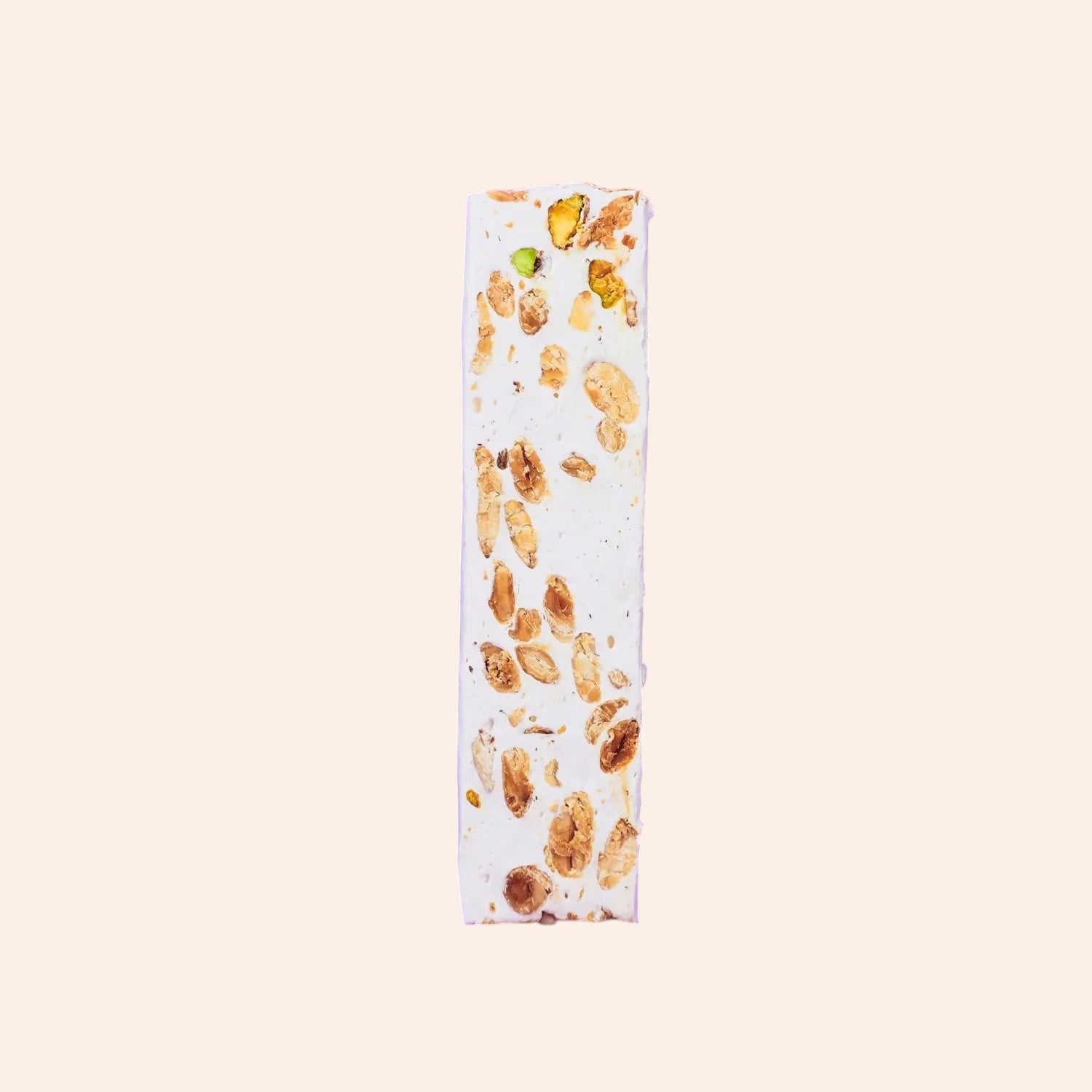 Barre de nougat Maison Fruidoraix tendre et blanche parsemée de pistaches entières sur fond clair