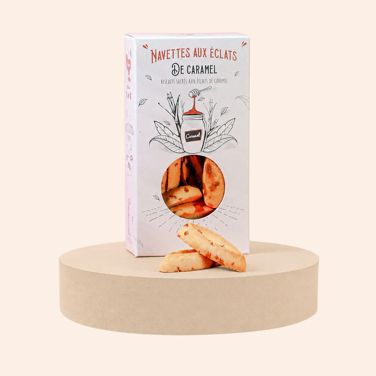 Boîte de navettes aux éclats de caramel Maison Fruidoraix posée sur un socle rond avec deux biscuits devant