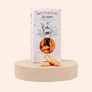 Boîte de navettes aux éclats de caramel Maison Fruidoraix posée sur un socle rond avec deux biscuits devant
