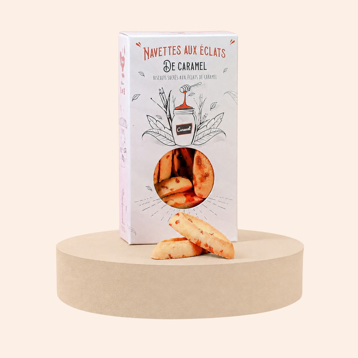 Boîte de navettes aux éclats de caramel Maison Fruidoraix posée sur un socle rond avec deux biscuits devant